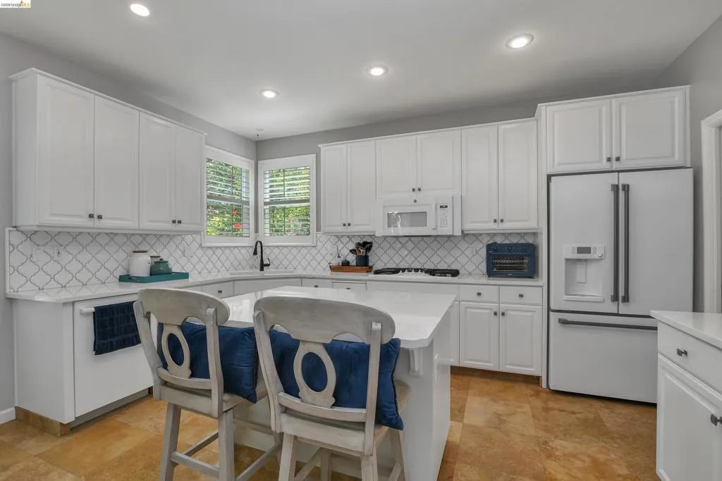 Kitchen featuring a breakfast bar, white appliances, white cabinetry, and recessed lighting
