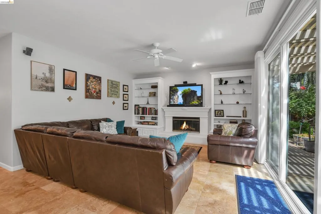 Family room featuring a fireplace, a ceiling fan, and built in shelves