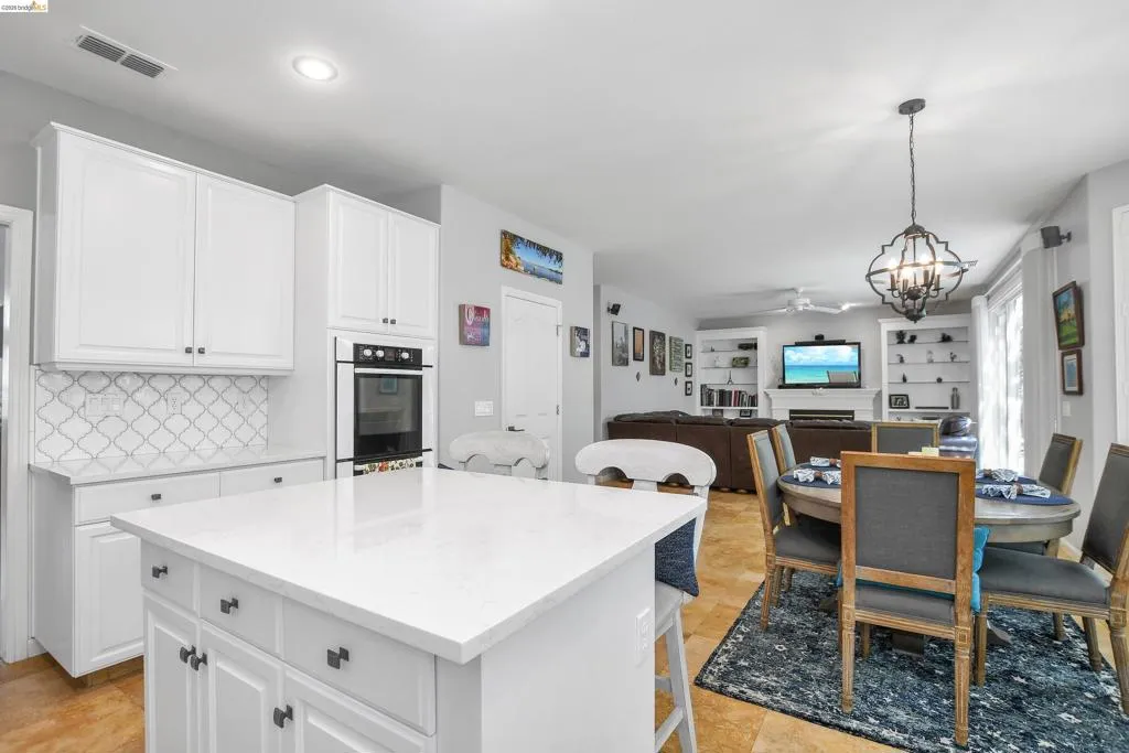 Kitchen with suspended lighting, a kitchen bar, open floor plan, and white cabinets