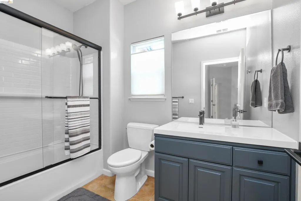 Bathroom featuring vanity, combined bath / shower with glass door, and light tile patterned flooring