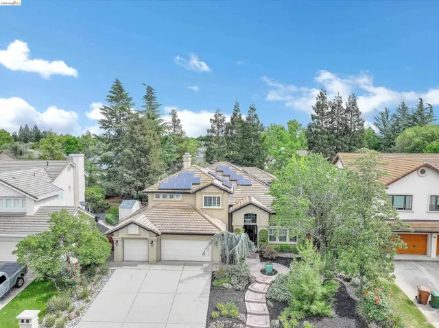 Traditional-style home featuring solar panels, concrete driveway, a garage, a tiled roof, and stucco siding