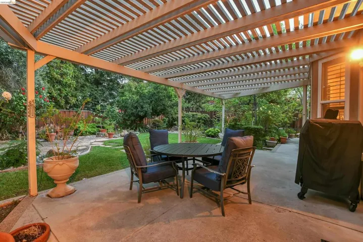 Fenced backyard with a patio, a grill, outdoor dining area, and a pergola