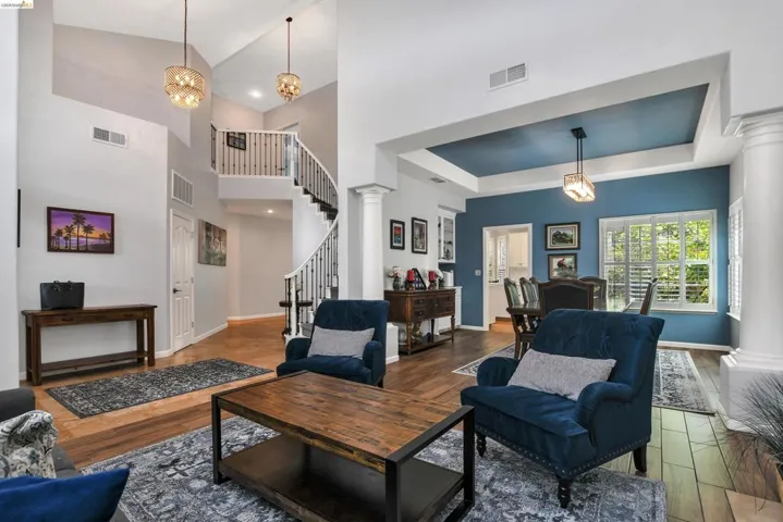 Living room featuring decorative columns, wood finished floors, a chandelier, and a high ceiling