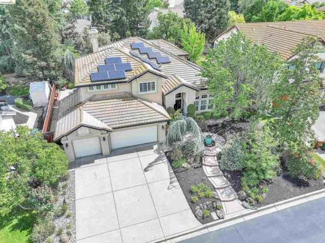 Traditional home with a tile roof, solar panels, driveway, an attached garage, and stucco siding