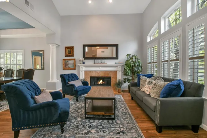 Living area featuring decorative columns, dark wood finished floors, a high ceiling, and a glass covered fireplace