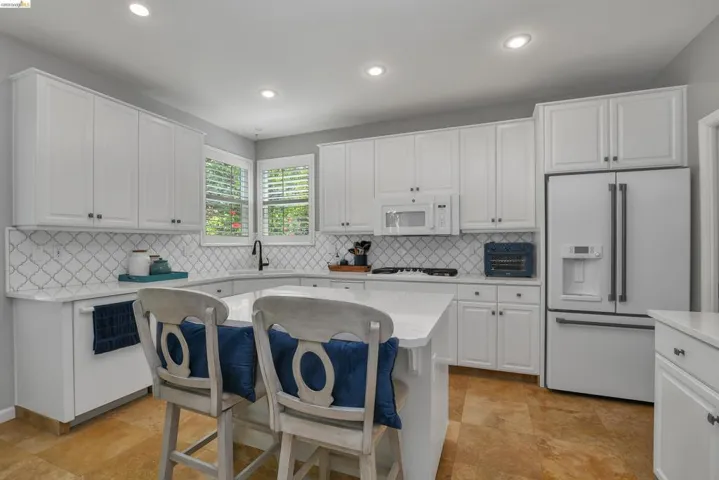 Kitchen featuring a breakfast bar, white appliances, white cabinetry, and recessed lighting