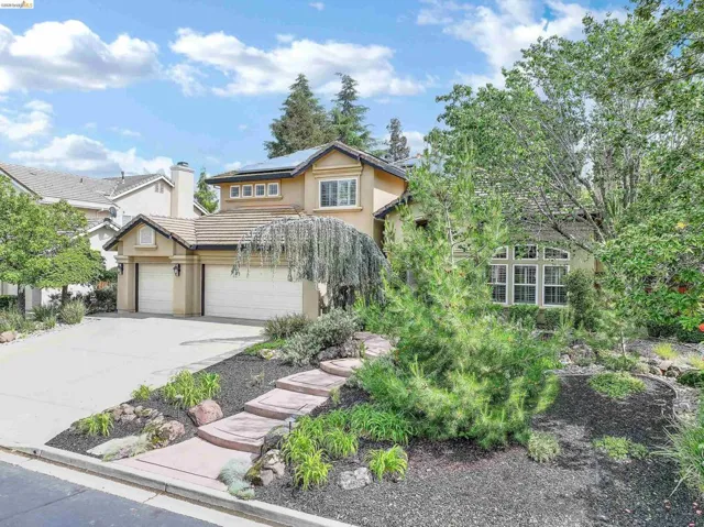 View of front of property with concrete driveway, stucco siding, solar panels, a tile roof, and a chimney