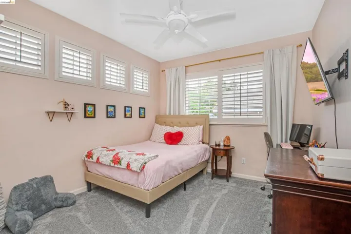 Bedroom with a ceiling fan, carpet flooring, and a desk