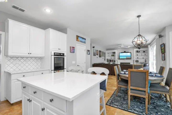 Kitchen with suspended lighting, a kitchen bar, open floor plan, and white cabinets