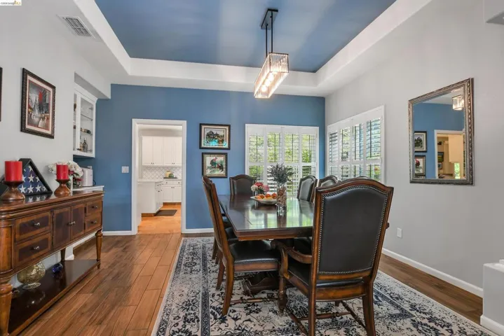 Dining room with a tray ceiling, wood finished floors, and hanging lights