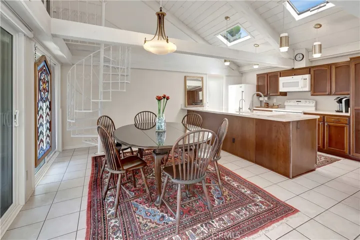 Dining and kitchen flooded with natural light from skylights and sliding glass doors.
