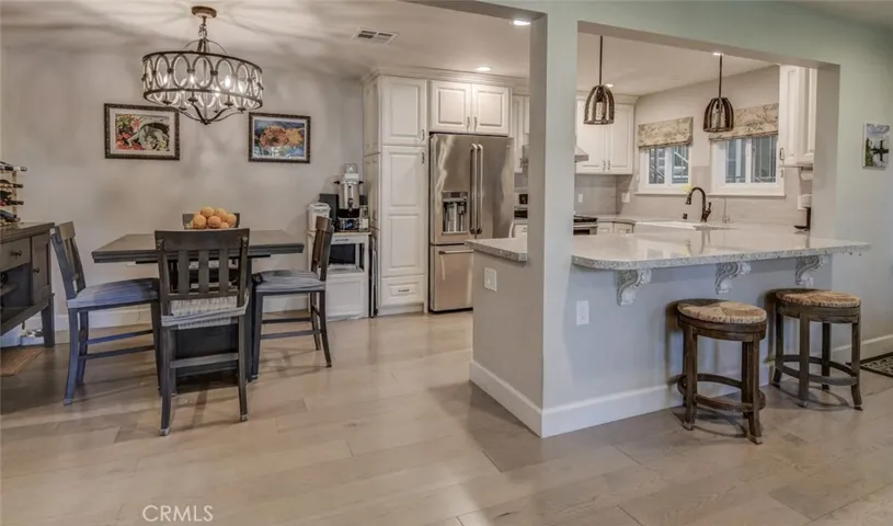 Dining area and kitchen from living area. Note the vinyl flooring throughout, the custom light fixtures and how bright the rooms show