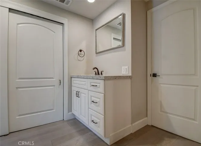 Master bath area with upgraded sliding doors to closet. Note the custom countertop, mirror and fixtures, cabinetry, and vinyl flooring