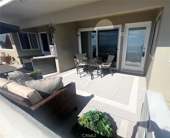 Front entryway has a covered patio facing the ocean view with a dining table and loveseat.