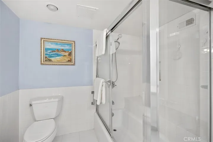 Shower in tub with built-in bench and glass enclosure.