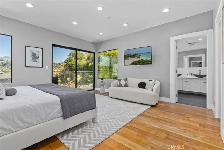 Spacious, contemporary bedroom with an en-suite bathroom. The space includes doors and windows that offer views of the canyon's greenery.