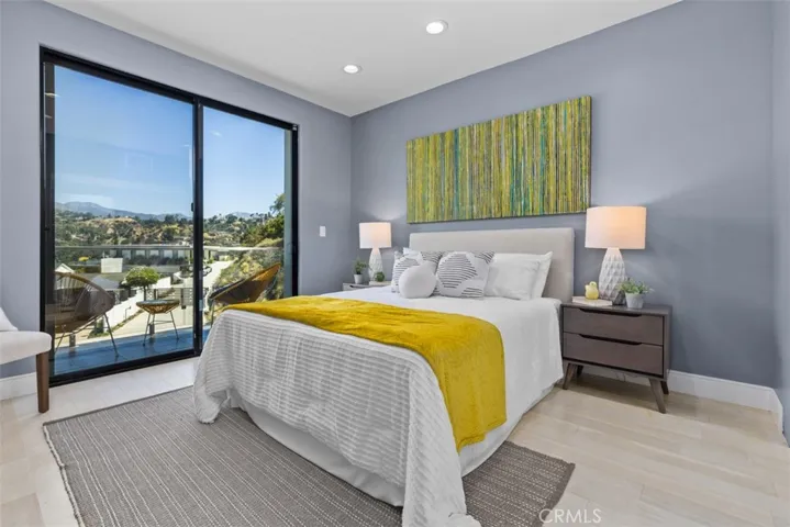 Through the glass doors, you can see a private balcony, a scenic view of the lush Chevy Chase Canyon hills, and clear blue sky.