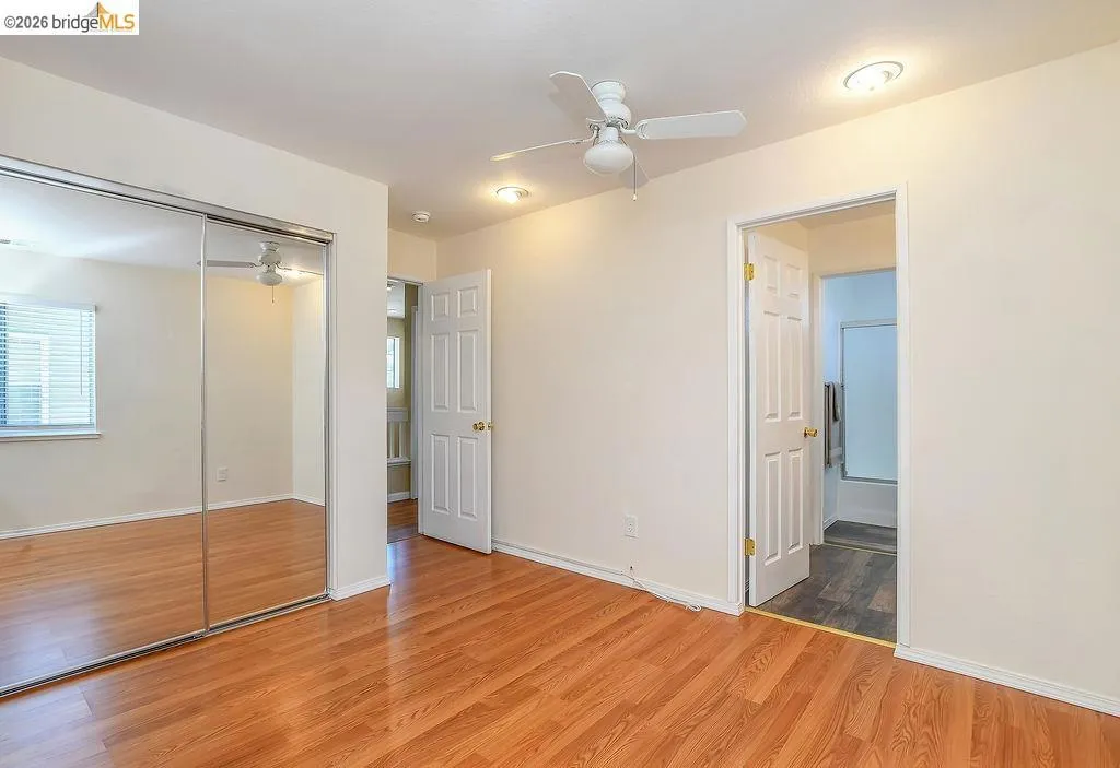 Bedroom featuring wood-finish flooring, mirrored closet doors, a ceiling fan with light, and recessed lighting