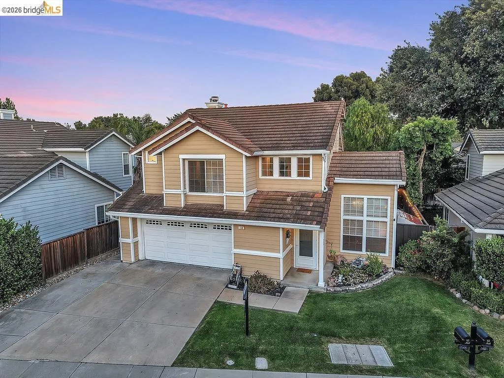 Two-story residence featuring light brown siding and a multi-gabled tile roof