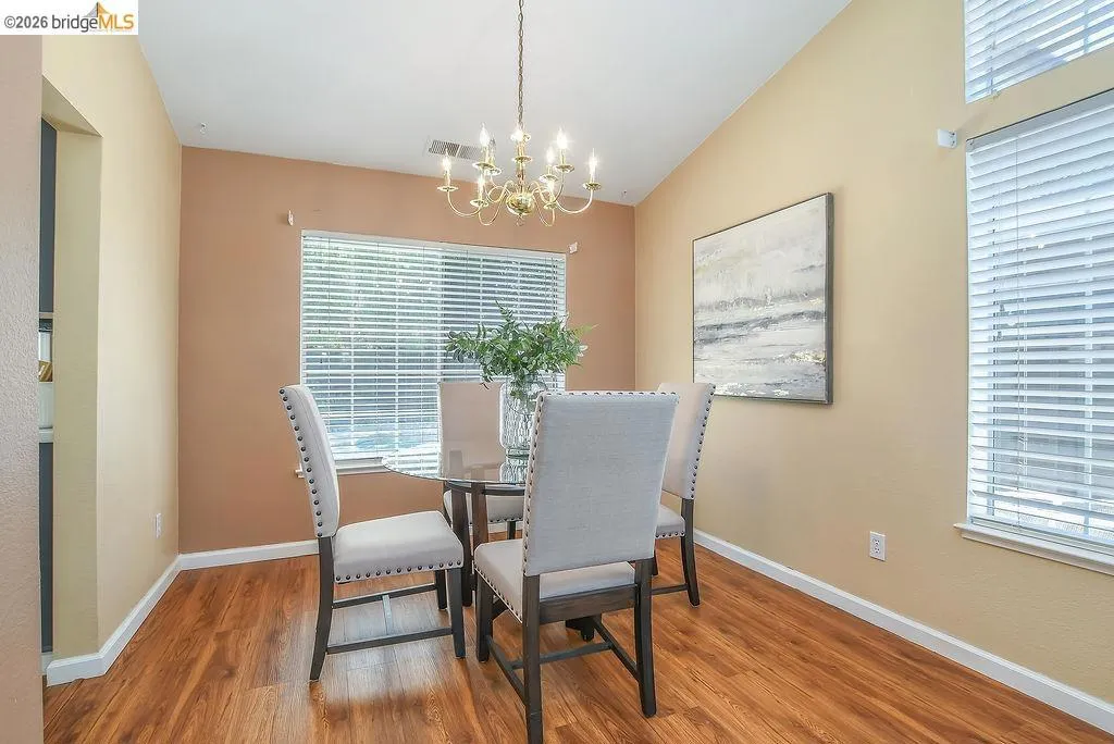 Dining space featuring wood-finish flooring, a brass-toned chandelier, and a vaulted ceiling