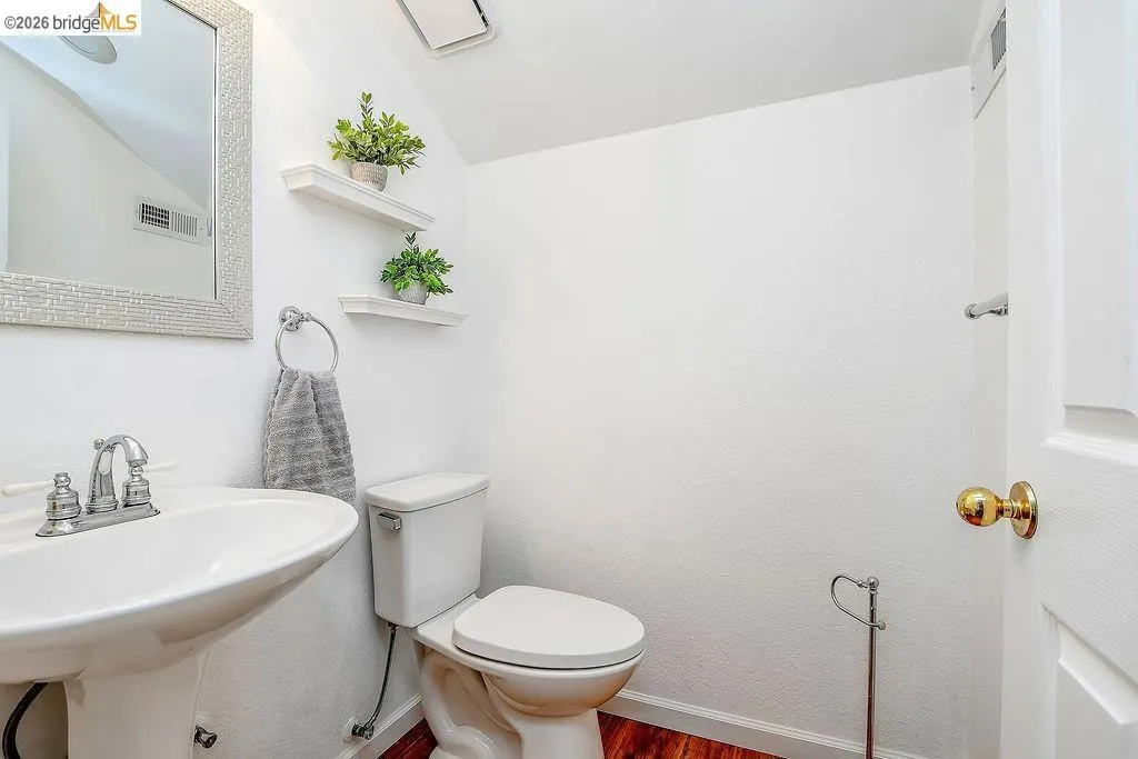 White pedestal sink with chrome faucet, complemented by a decorative framed mirror