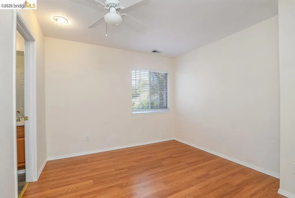 Room featuring wood-finish flooring, a ceiling fan, recessed lighting, and a window with blinds