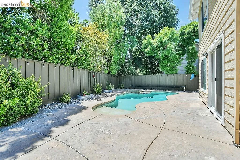 Curved swimming pool surrounded by a stamped concrete patio