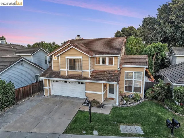 Two-story residence featuring light brown siding and a multi-gabled tile roof