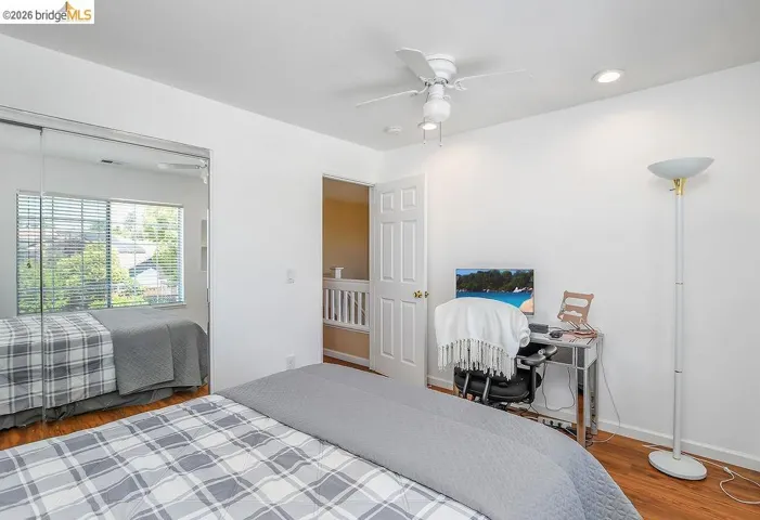 Bedroom featuring wood-finish flooring, a ceiling fan, recessed lighting, and a mirrored closet