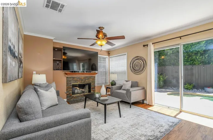 Living area featuring a stone-clad fireplace with wood mantel, ceiling fan, and wood-finish flooring