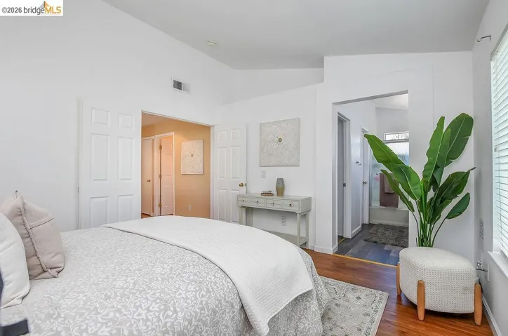 Bedroom featuring vaulted ceilings, wood-finish flooring, and white paneled doors