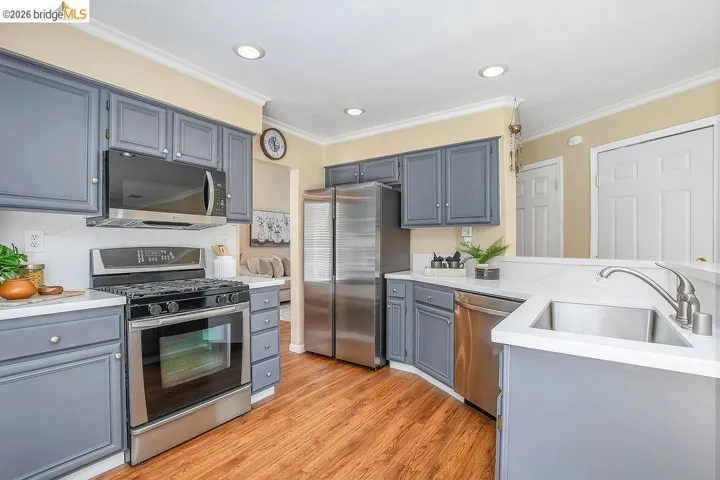 Kitchen featuring wood-finish flooring, recessed lighting, stainless steel appliances, white countertops, and gray cabinetry