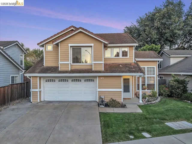 Two-story residence featuring light brown siding and a multi-gabled roof