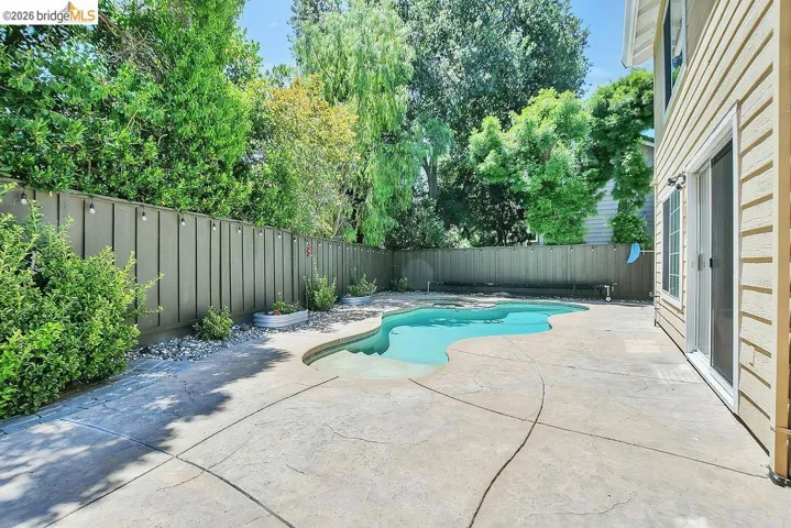 Curved swimming pool surrounded by a stamped concrete patio