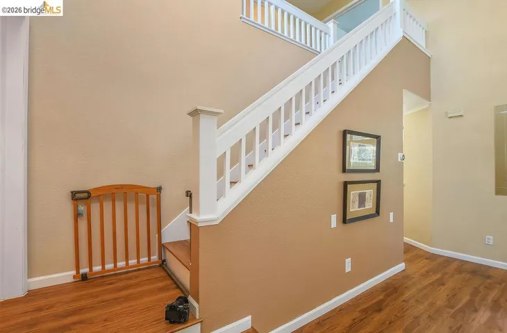 Two-story interior entryway featuring wood-finish flooring, a white spindle staircase, and neutral-toned wall paint