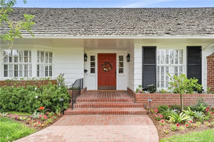 View of front door entry by way of brick walkway.