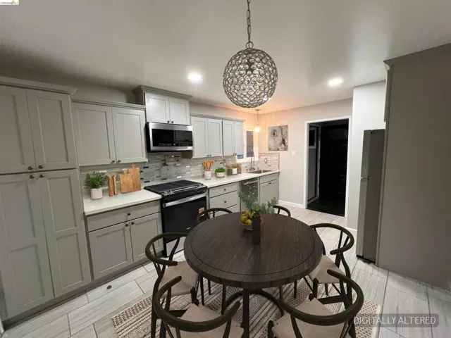 Kitchen featuring stainless steel appliances, backsplash, decorative light fixtures, and gray cabinets