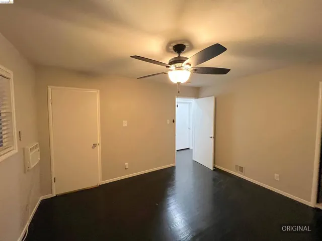 Unfurnished bedroom with dark wood-type flooring and a ceiling fan