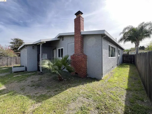 Rear view of house featuring a fenced backyard, stucco siding, and a chimney