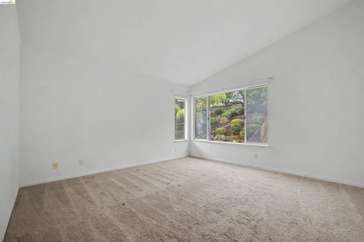 Unfurnished room with carpet flooring and vaulted ceiling