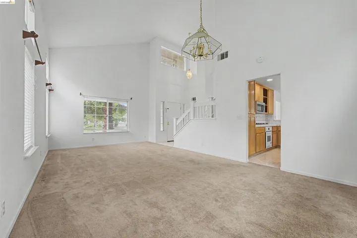 Unfurnished living room featuring light carpet, a chandelier, and a high ceiling