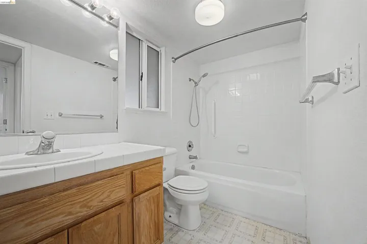 Bathroom featuring vanity, bathing tub / shower combination, and light flooring