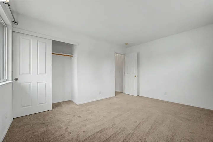 Unfurnished bedroom with light carpet and a closet