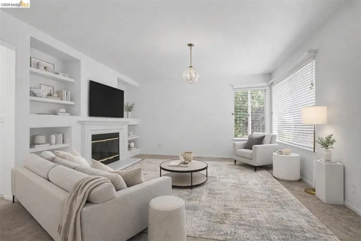 Living room with built in features, carpet floors, and a glass covered fireplace