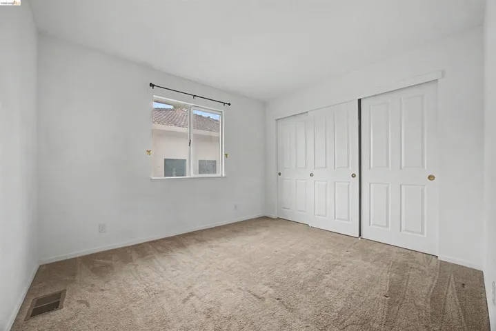 Unfurnished bedroom with light colored carpet and a closet