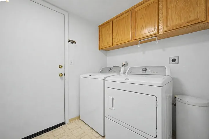 Laundry room with light floors, cabinet space, and washer and dryer