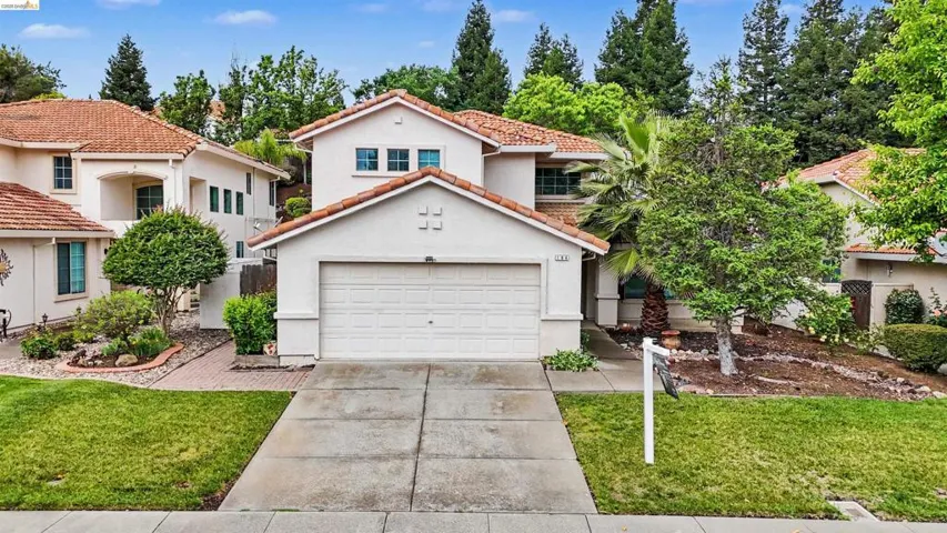 Mediterranean / spanish house featuring concrete driveway, stucco siding, a front yard, and a tiled roof