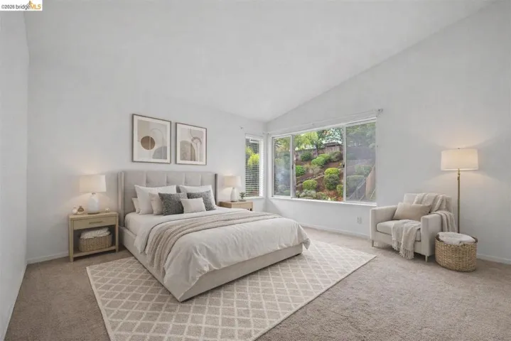 Carpeted bedroom with vaulted ceiling and baseboards