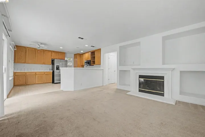 Unfurnished living room with light colored carpet, a ceiling fan, recessed lighting, and a glass covered fireplace