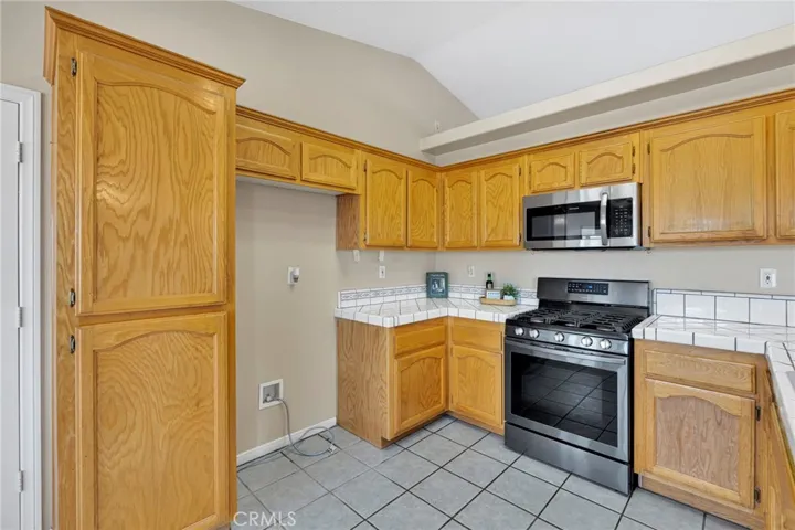 Kitchen with tile counters and wood cabinets with pantry cabinet